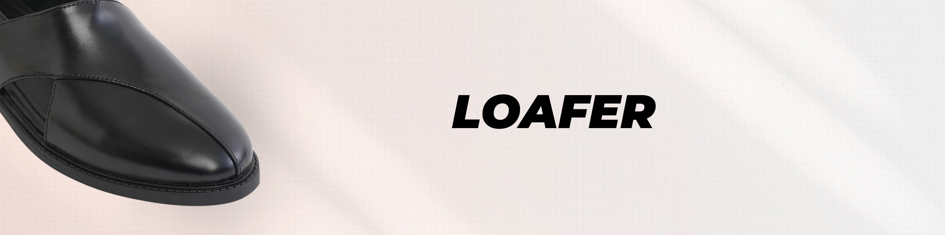 A close-up of a black leather loafer shoe on the left side with the word 'LOAFTER' in bold black text on a light off-white background.