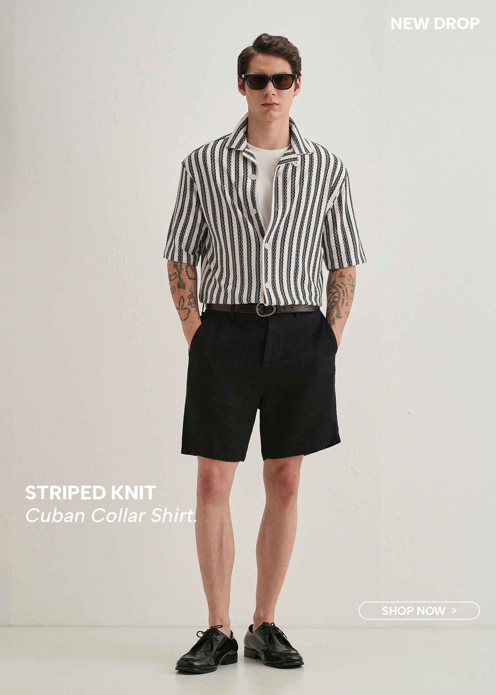 Man wearing a striped knit Cuban collar shirt and black shorts on a white background