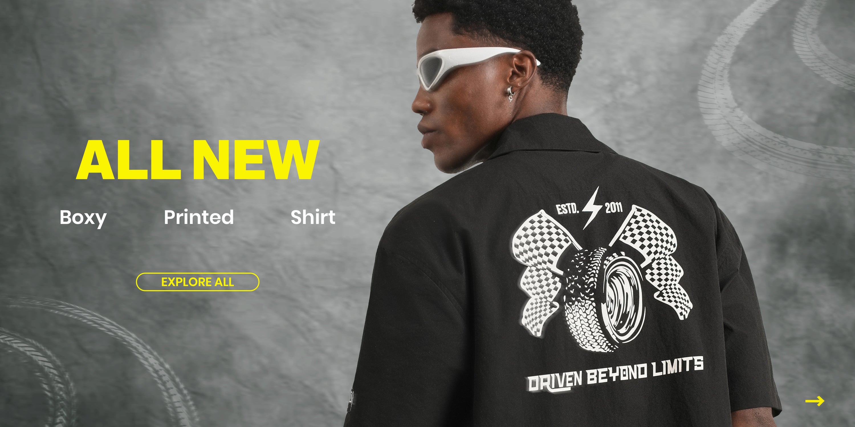 A person shown from the back wearing a black short-sleeve shirt with a large white graphic print on the back, set against a textured gray background with promotional text on the left.
