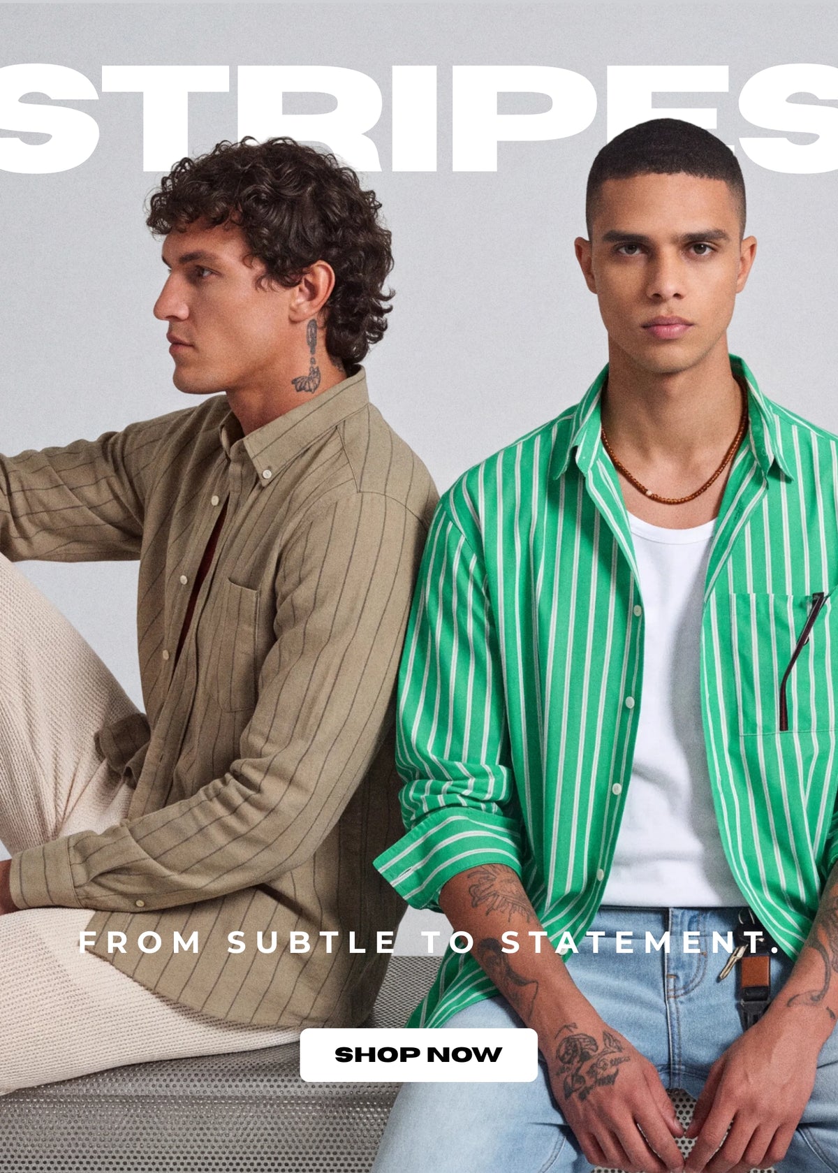 Two male models wearing striped button-down shirts in a studio setting. The model on the left wears a muted olive-beige pinstripe shirt, and the model on the right wears a bright green and white striped shirt over a white t-shirt.